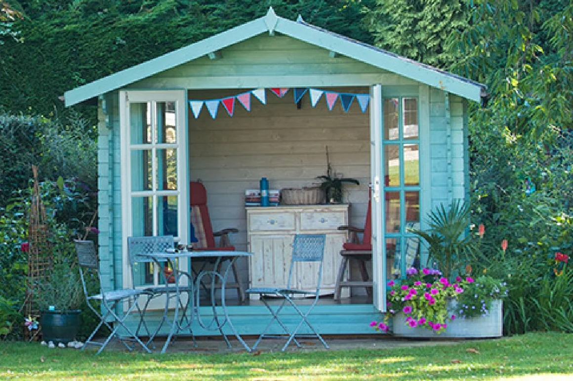 Hellblaues Gartenhaus mit geöffneten Türen, darin Gartenmöbel und Dekoration.